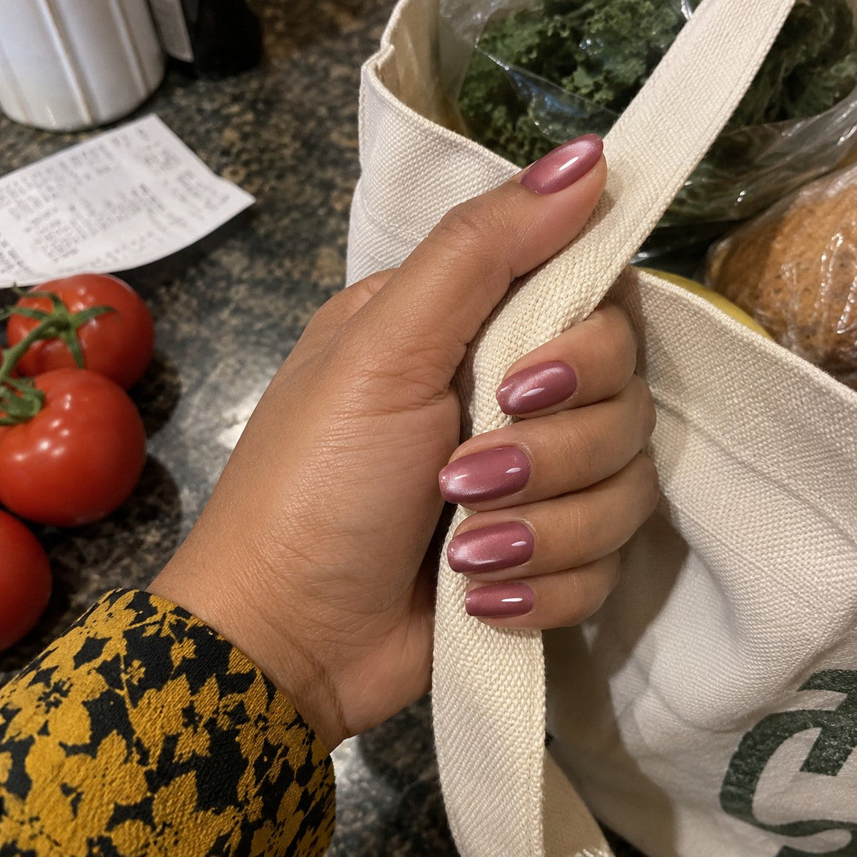 Ebony Rose cat-eye nails holding a canvas tote bag